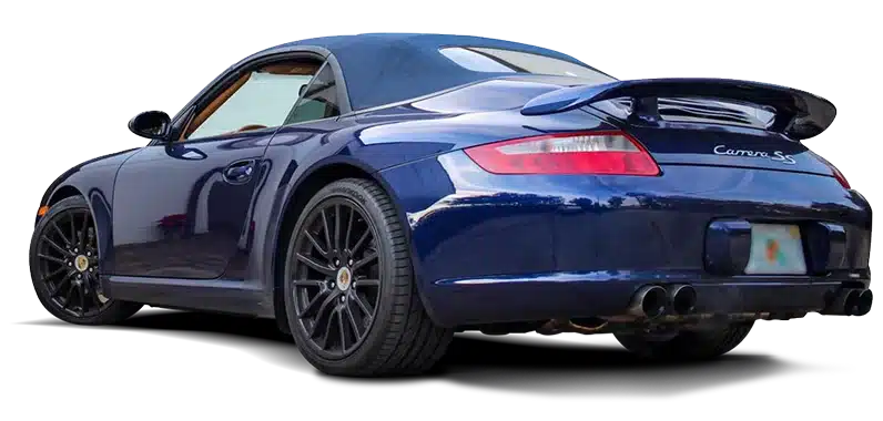 A sleek, dark blue sports car with black alloy wheels and a rear spoiler, parked and viewed from the back and side. The cars roof is up, and the license plate is blurred.