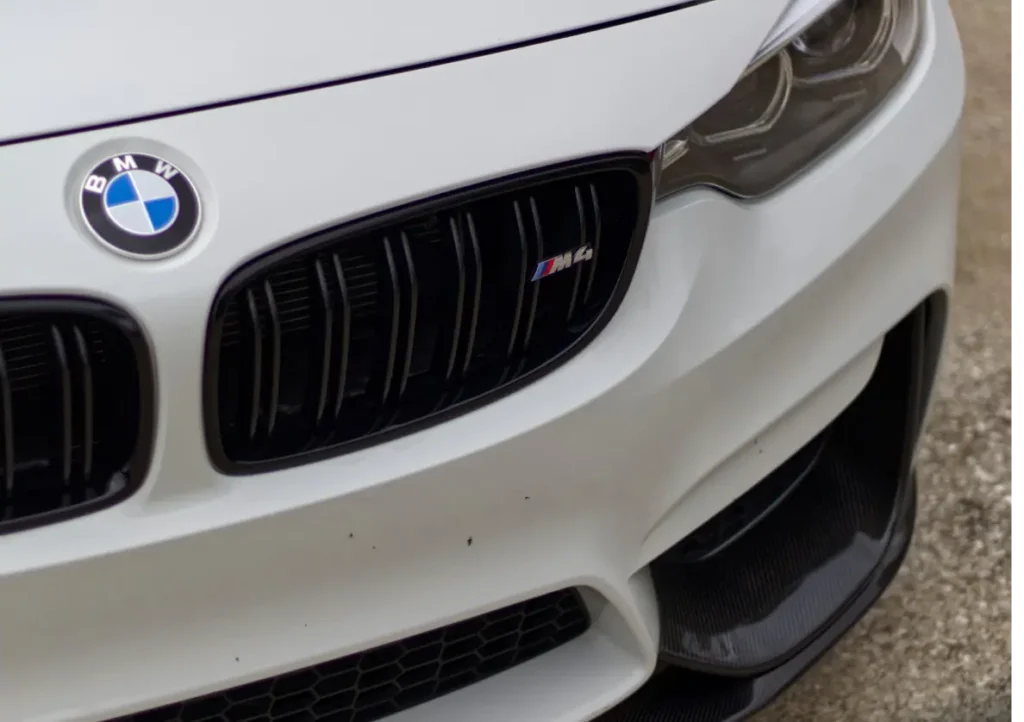 bmw, auto repair in Jacksonville, FL at Mack Motorwerks. Close-up of a white BMW with a focus on the front grille. The BMW badge is visible, and the grille displays an M4 emblem. The sleek design and black detailing add to the cars sporty appearance.